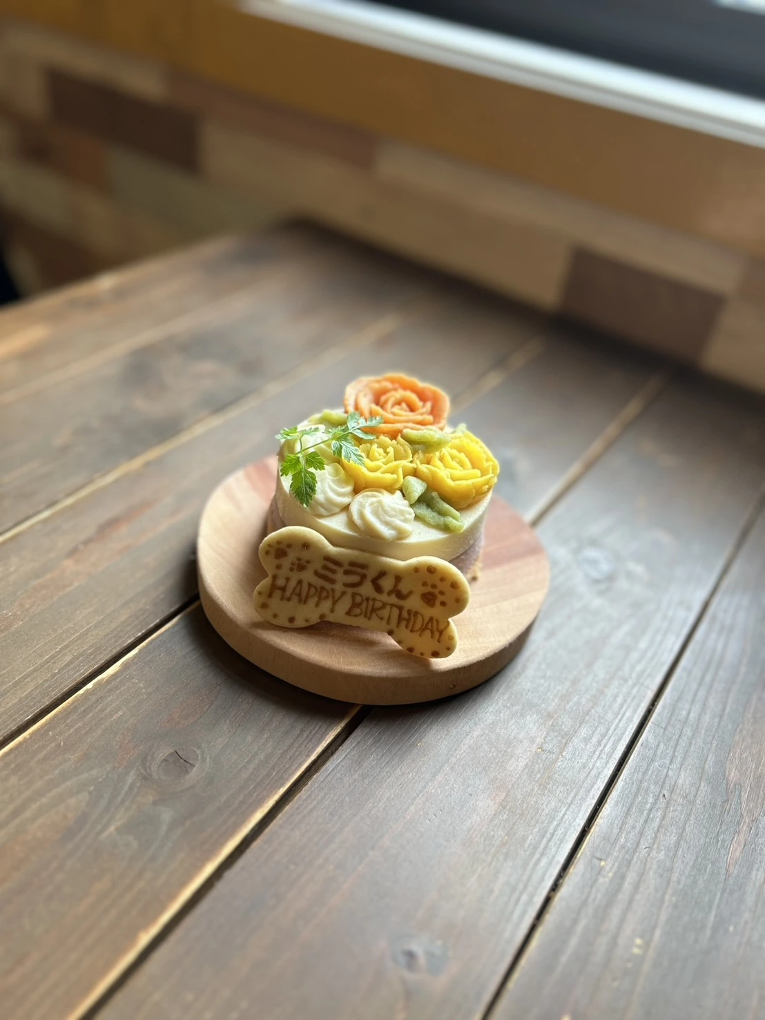 花の飾りとメッセージクッキーを添えたわんちゃん用お祝いケーキ